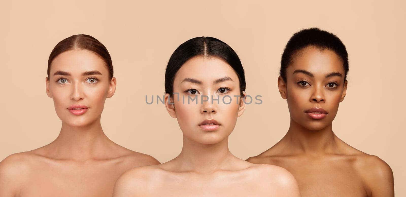 Portrait Of Three Sensual Diverse Girls Wrapped In Bath Towels Standing Posing In Studio Over Gray Background. Beauty Spa Concept.