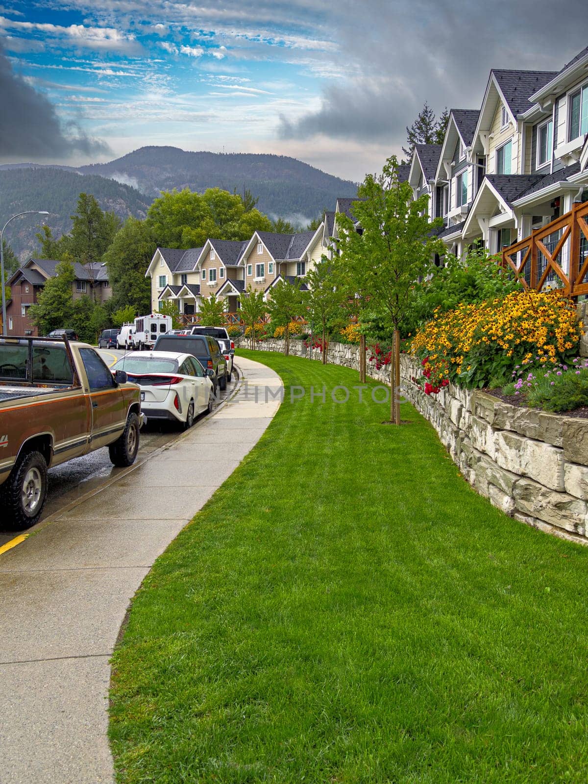 Row of residencial townhouses with cars parked on the street after the rain.
