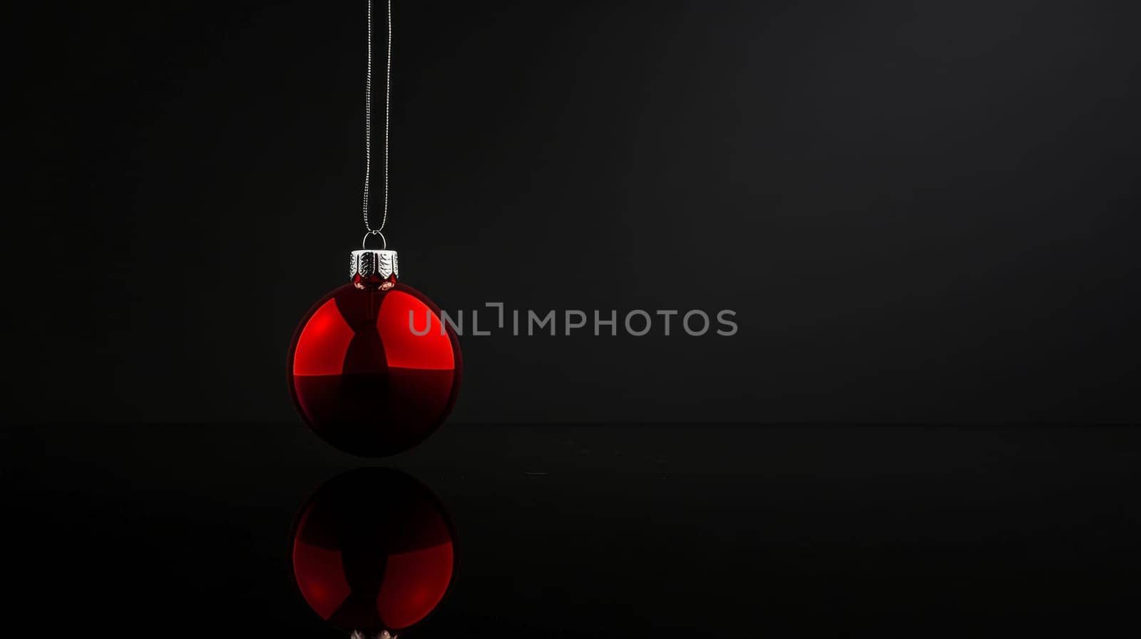 Red christmas ornament with reflection on black background, minimalistic holiday concept.