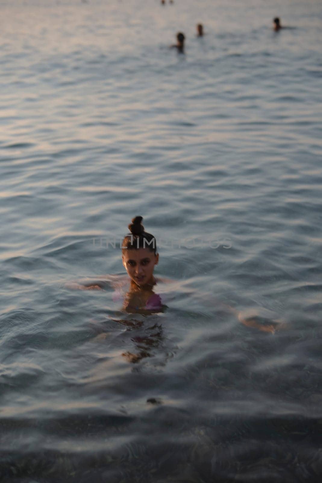A breathtaking moment of tranquility as a young girl enjoys the serene calm waters during the sunset hour