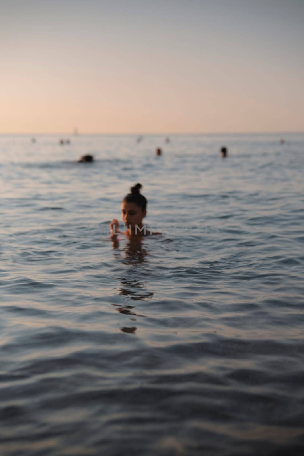 A beautifully tranquil scene of an individual swimming gracefully at sunset, surrounded by calm ocean waters