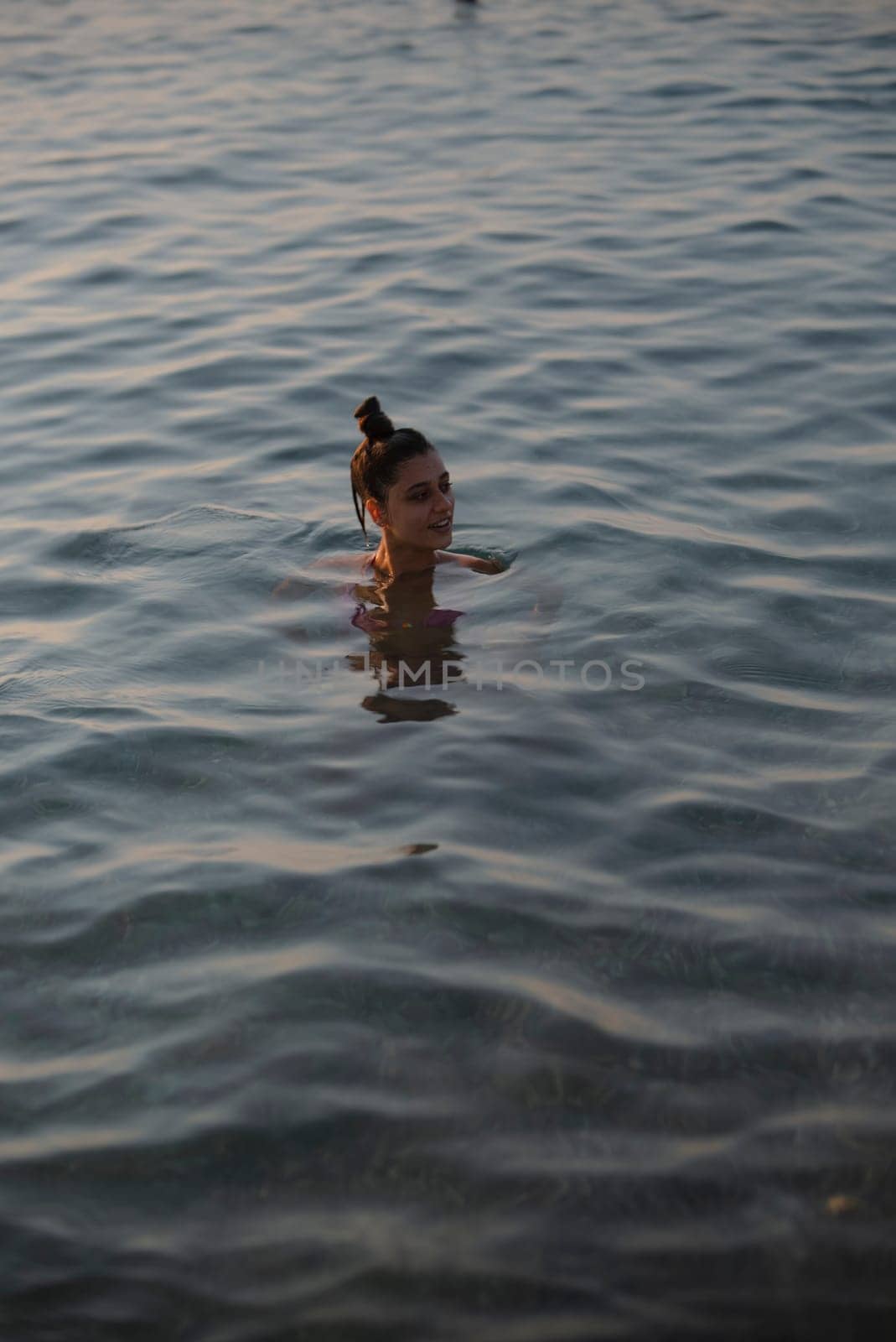 A beautiful and tranquil moment is captured as a woman swims peacefully in the reflective water surface, evoking calm