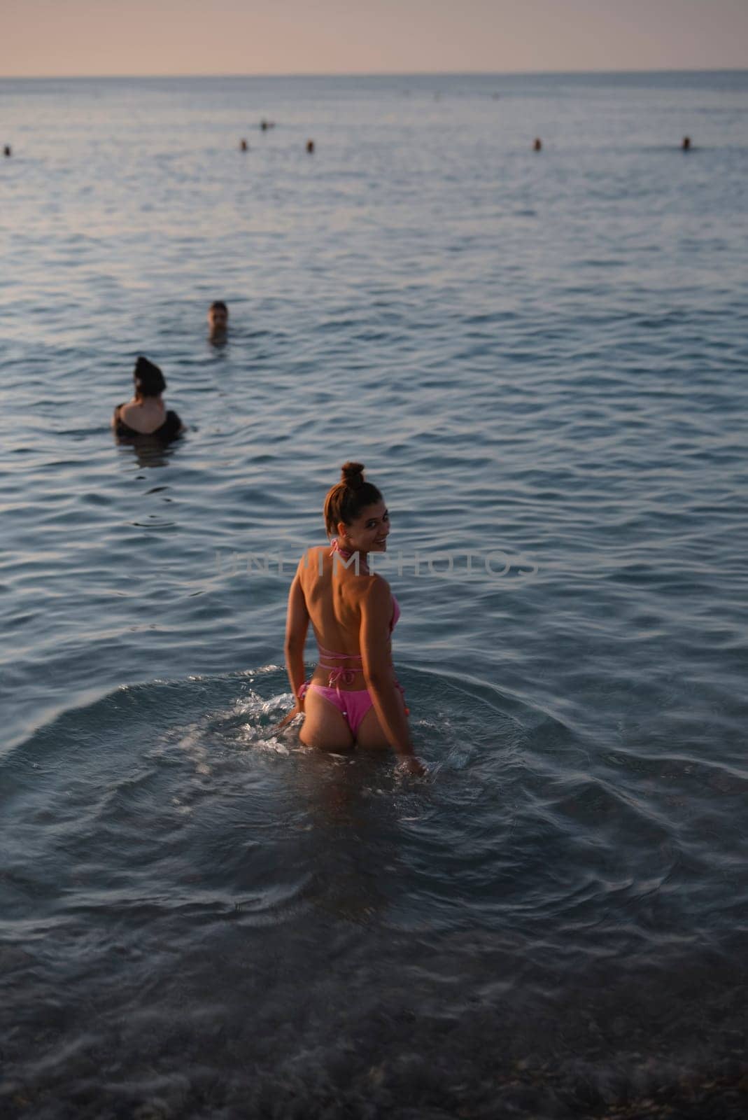 Groups of people are enjoying a peaceful and relaxing evening in the tranquil waters while watching the sunset