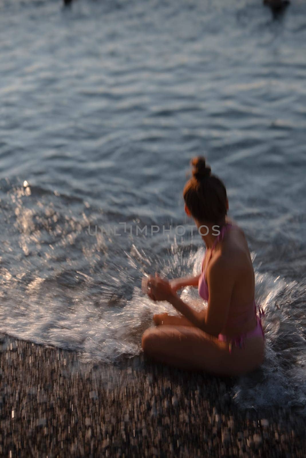 A young girl happily splashes around in the cool water, thoroughly enjoying a bright and sunny day by the sea