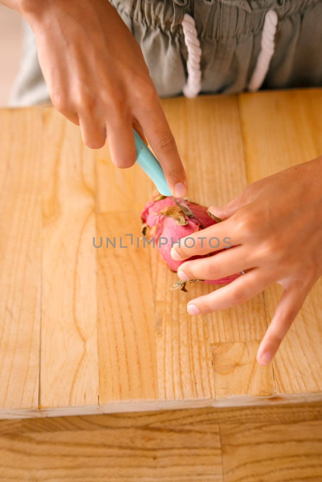 A person skillfully slicing a vibrant dragon fruit on polished wood, showcasing a delightful moment of freshness
