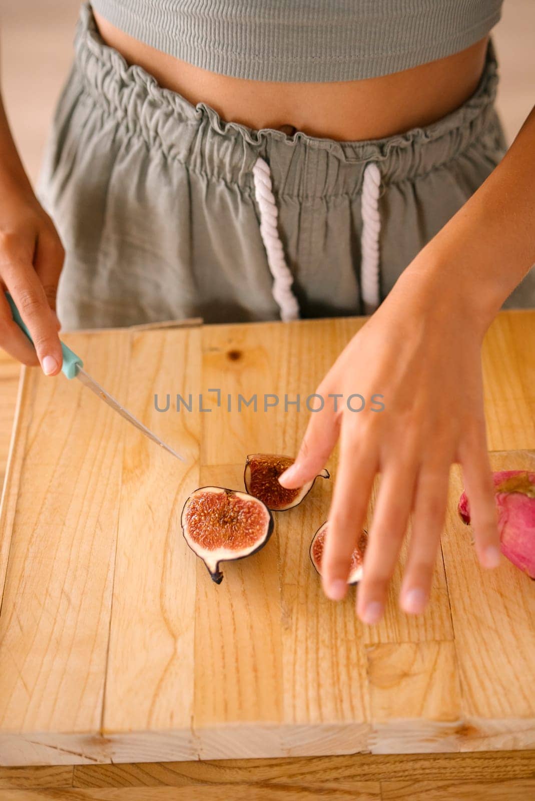 A person skillfully slices a ripe fig on a rustic countertop, showcasing impressive culinary skills