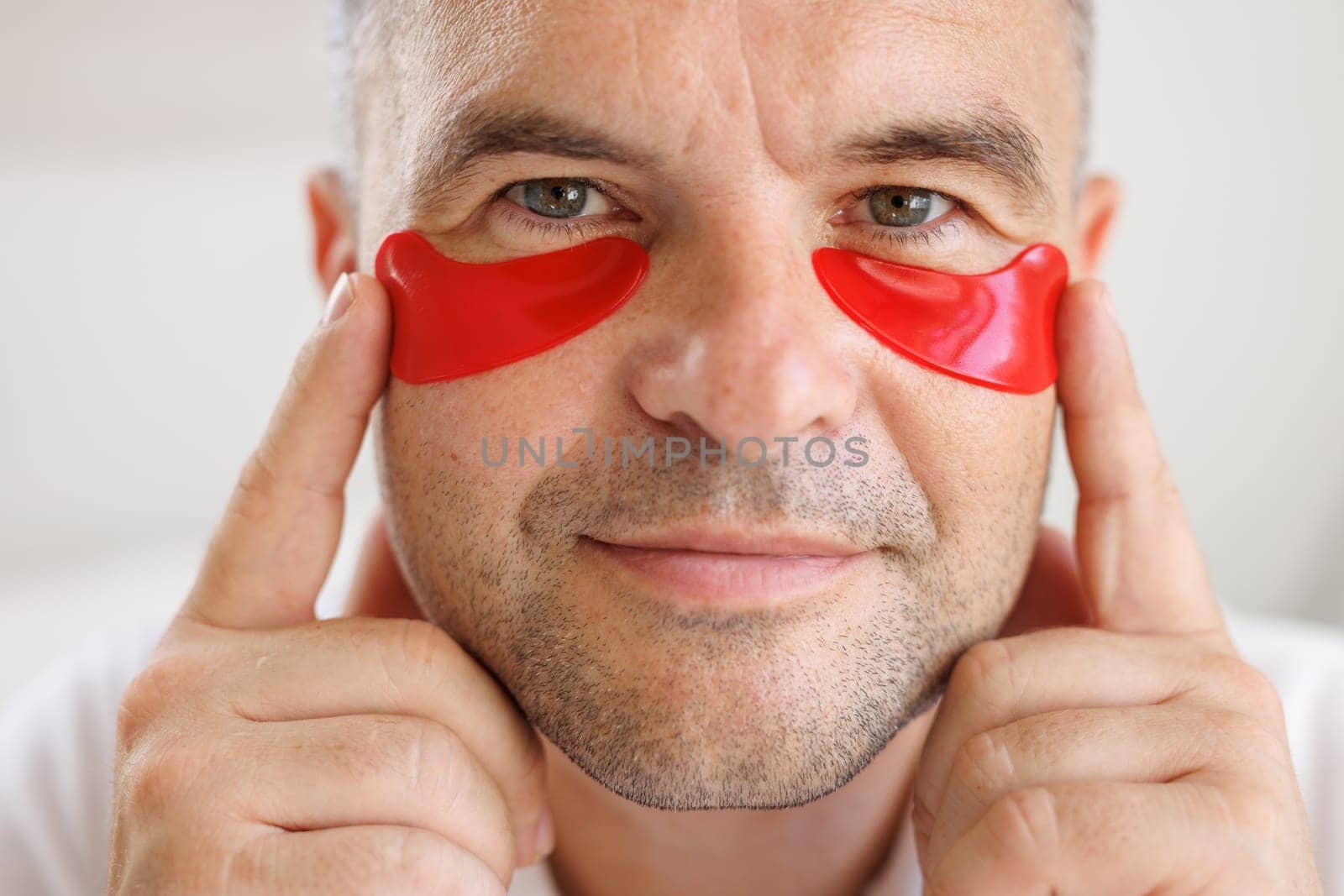 man applying eye patches to face. Wrinkles and facial care at home for men. concept of facial rejuvenation