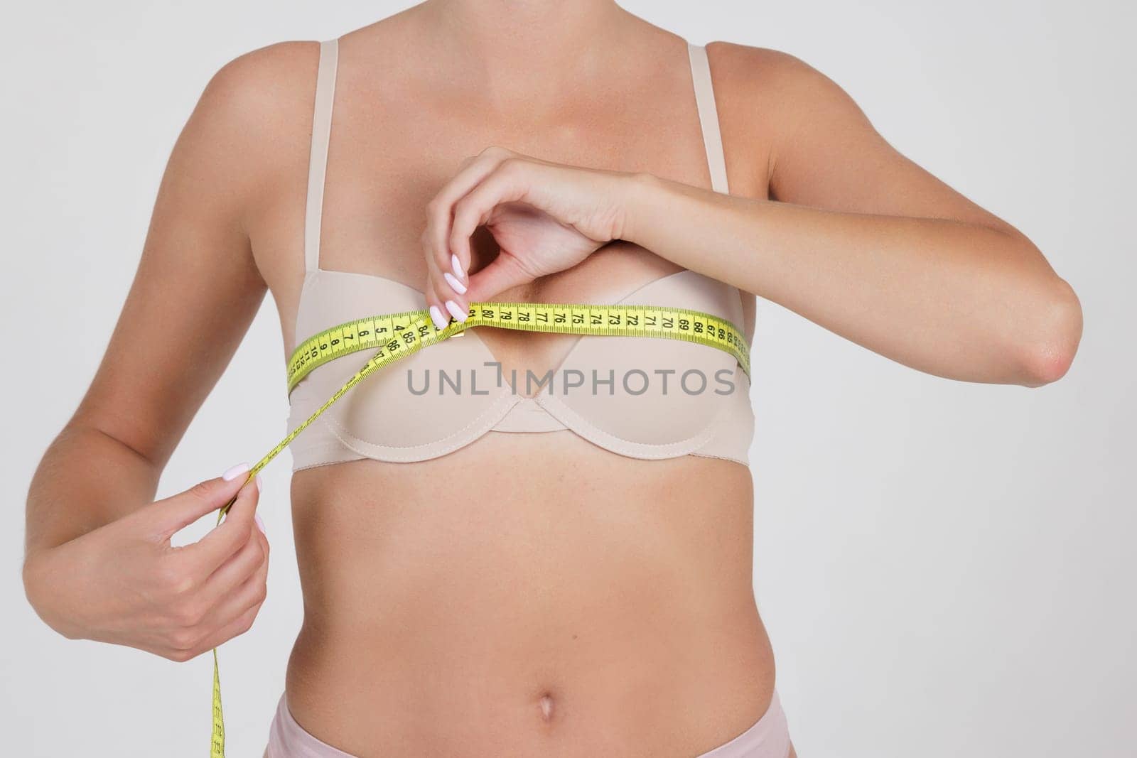 girl measuring breast size close up on white background. concept of increasing breast size, Mammoplasty