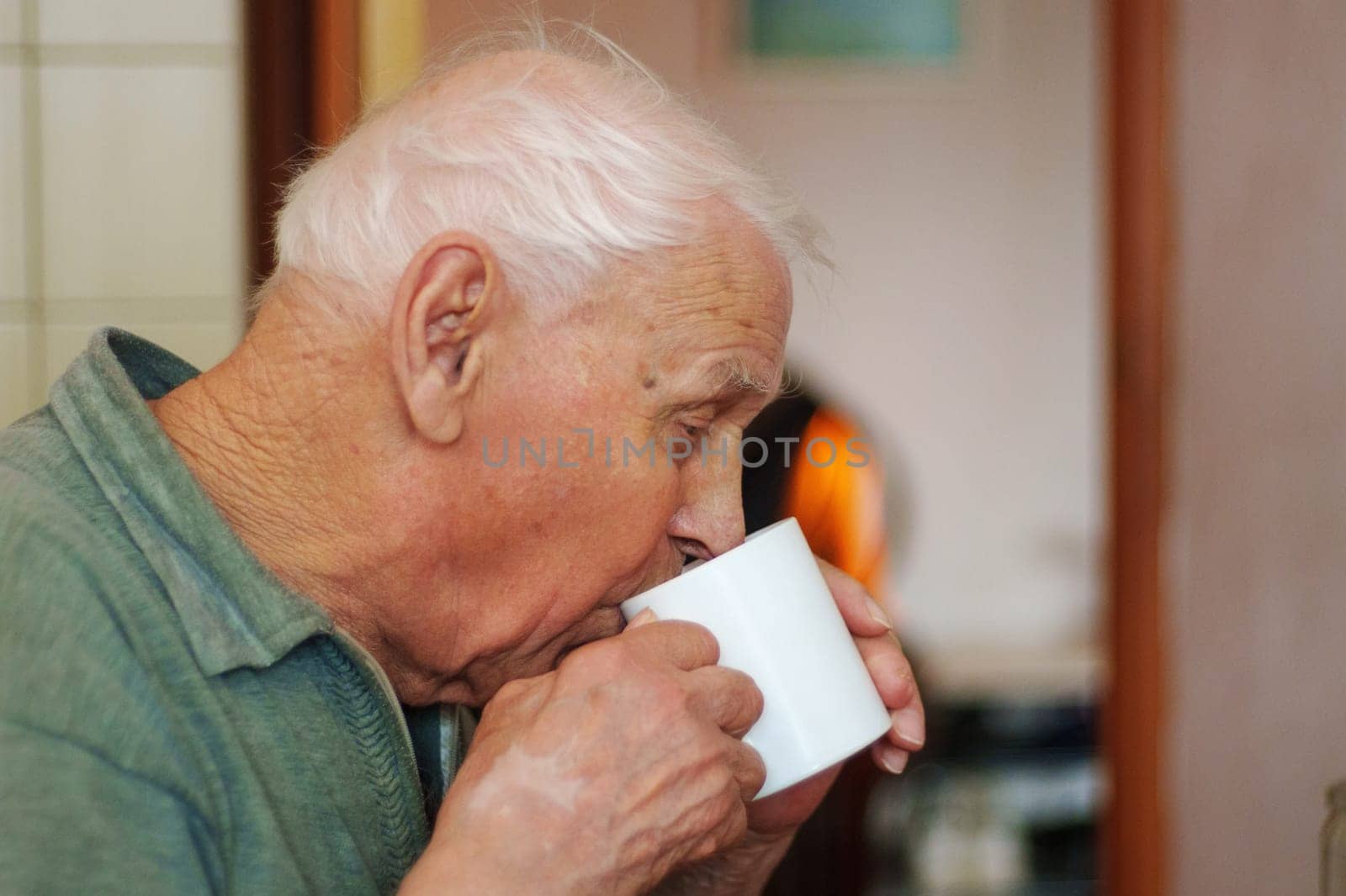 An elderly man takes a moment to savor a warm drink, quietly reflecting as he enjoys the comforting