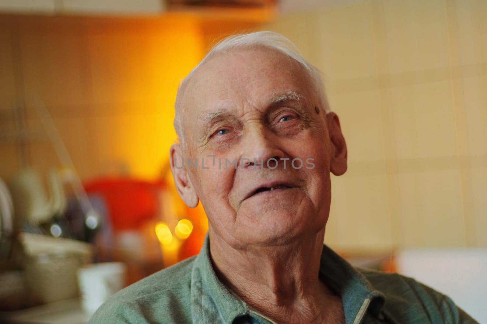 An elderly man smiles warmly while seated in a cozy kitchen during the late afternoon, surrounded by a homely atmosphere