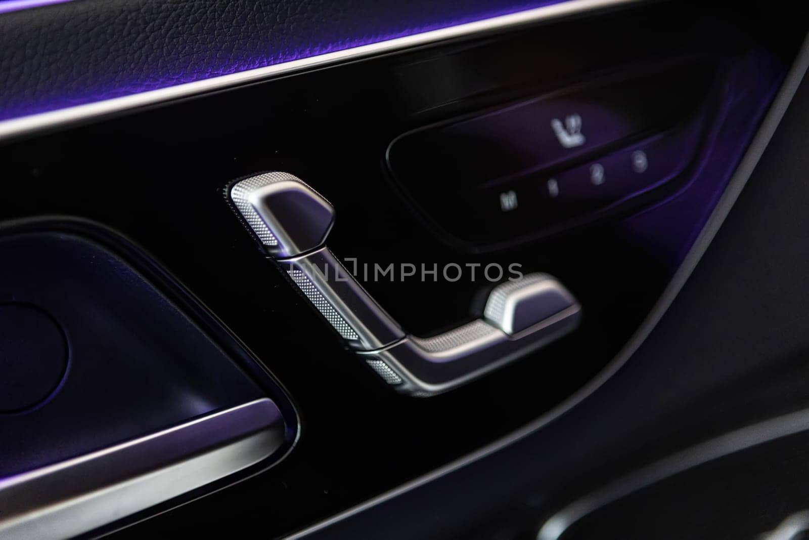 Close-up of a car door interior, showcasing luxurious leather materials and advanced seat adjustment controls, complemented by ambient lighting for a premium driving experience.