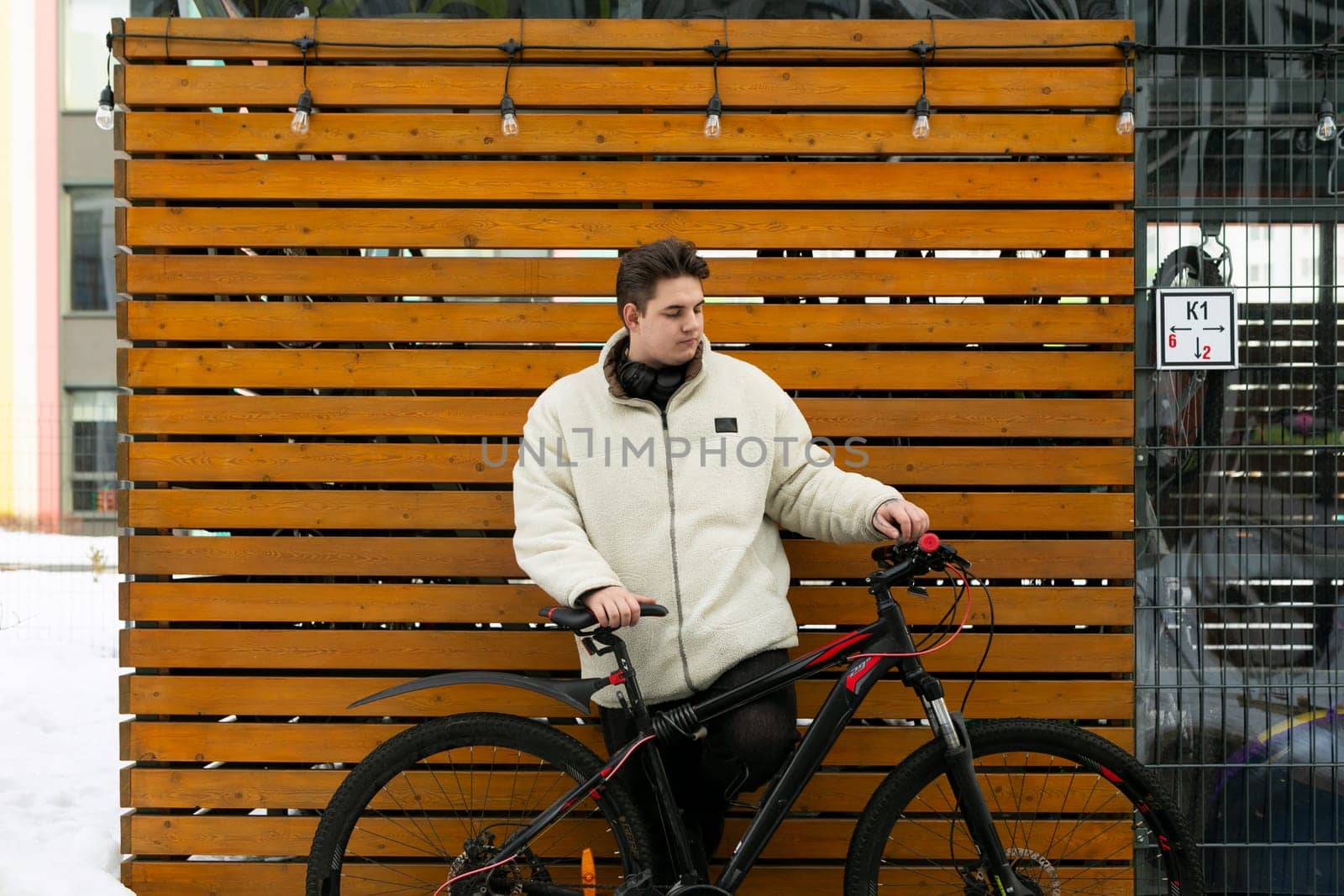 A young European man with a winter jacket took his bike outside.