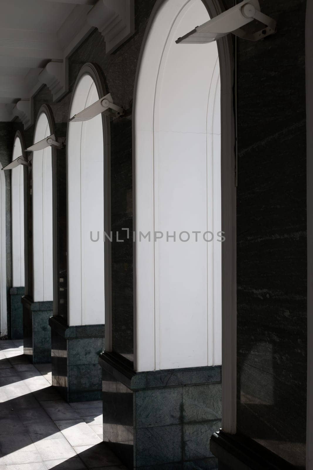 The arched windows are made of marble and are illuminated by sunlight. The light casts shadow on the floor, creating sense of depth and dimension
