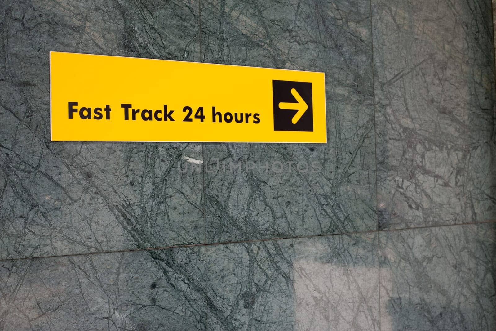 Sign on the wall indicating the direction of travel to access the fast track, convenient guide on wall of building when traveling