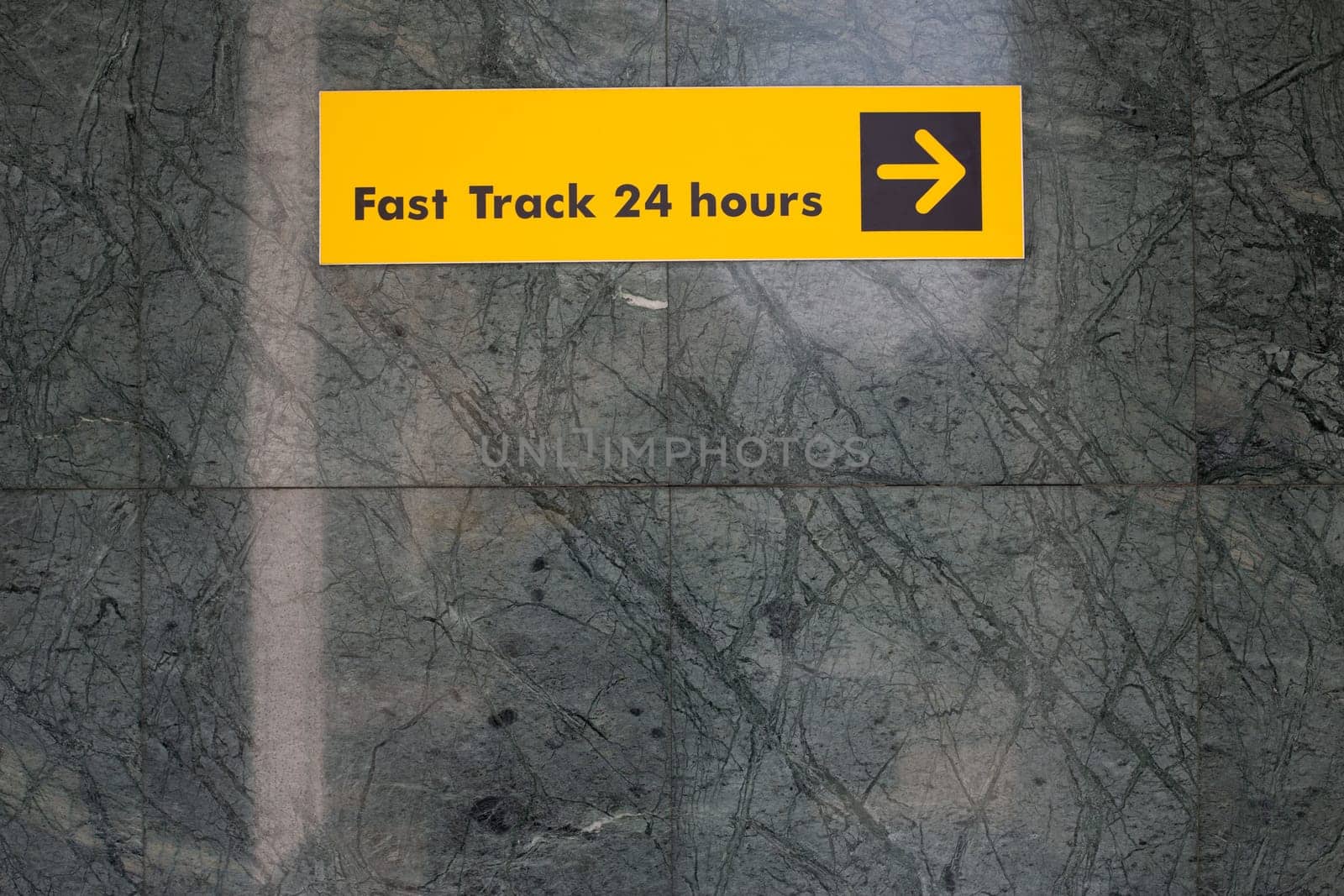 Sign on wall that says Fast Track 24 Hours and arrow for way. Sign to help guide you in an unfamiliar place for travelers on wall