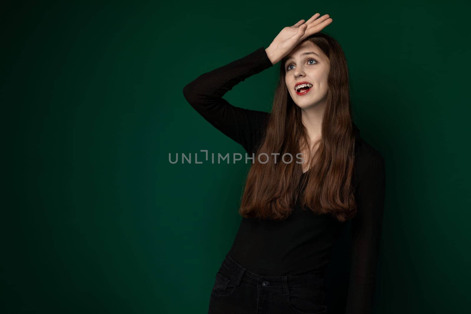 A woman, dressed in a black shirt, is striking a pose for a photograph. She is standing confidently and looking directly at the camera, showcasing her stylish outfit.