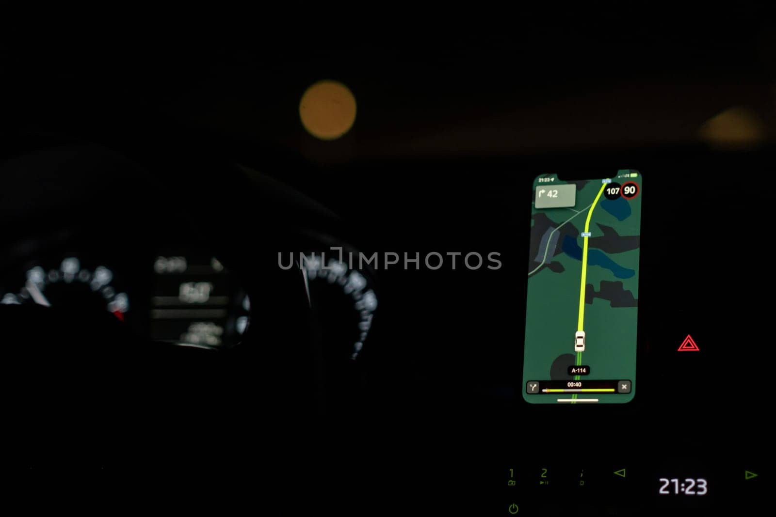 A driver uses a GPS navigation system at night, displaying route information and speed while ensuring a safe journey.
