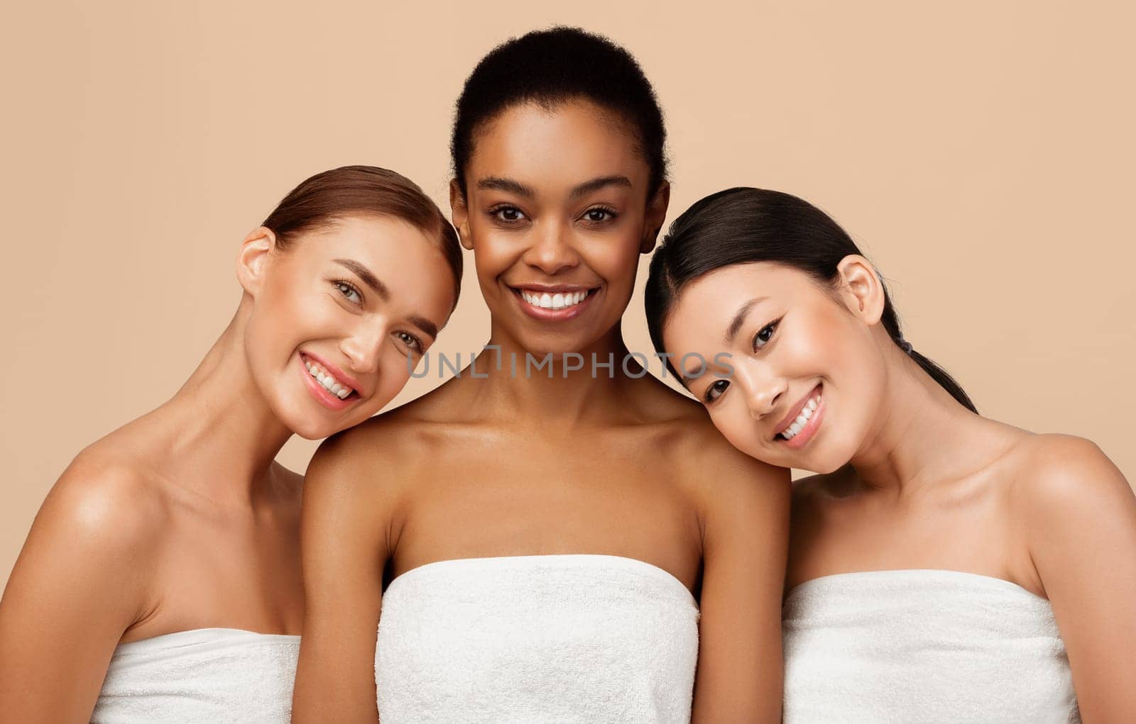 Beauty Of Body. Three Multiracial Women Wrapped In Towels Posing Smiling To Camera Standing On Gray Background