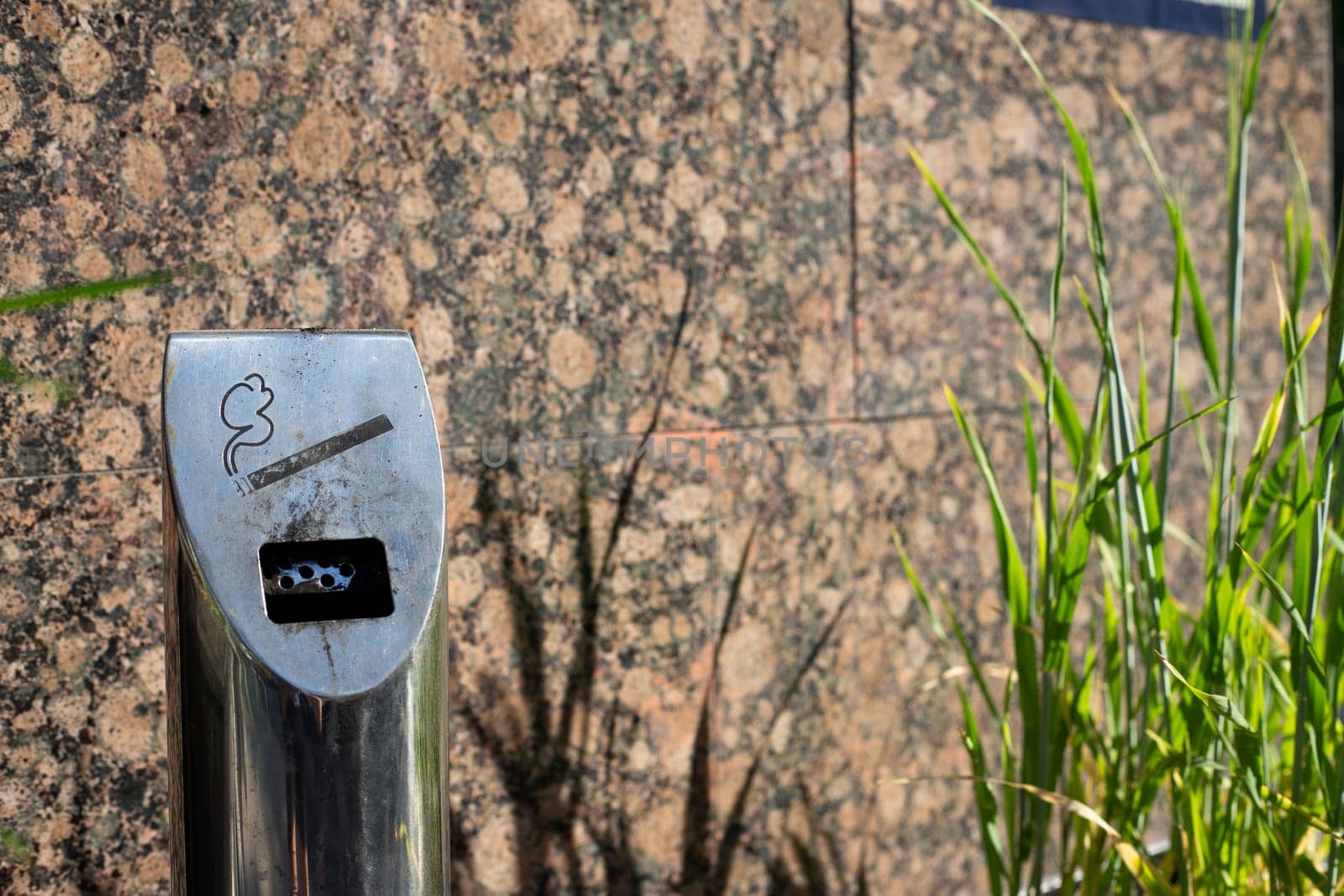 Modern ashtray on street in smoking area, metal pole with compartment for disposing of cigarettes, health problems of smoking of the population people on city street in public place