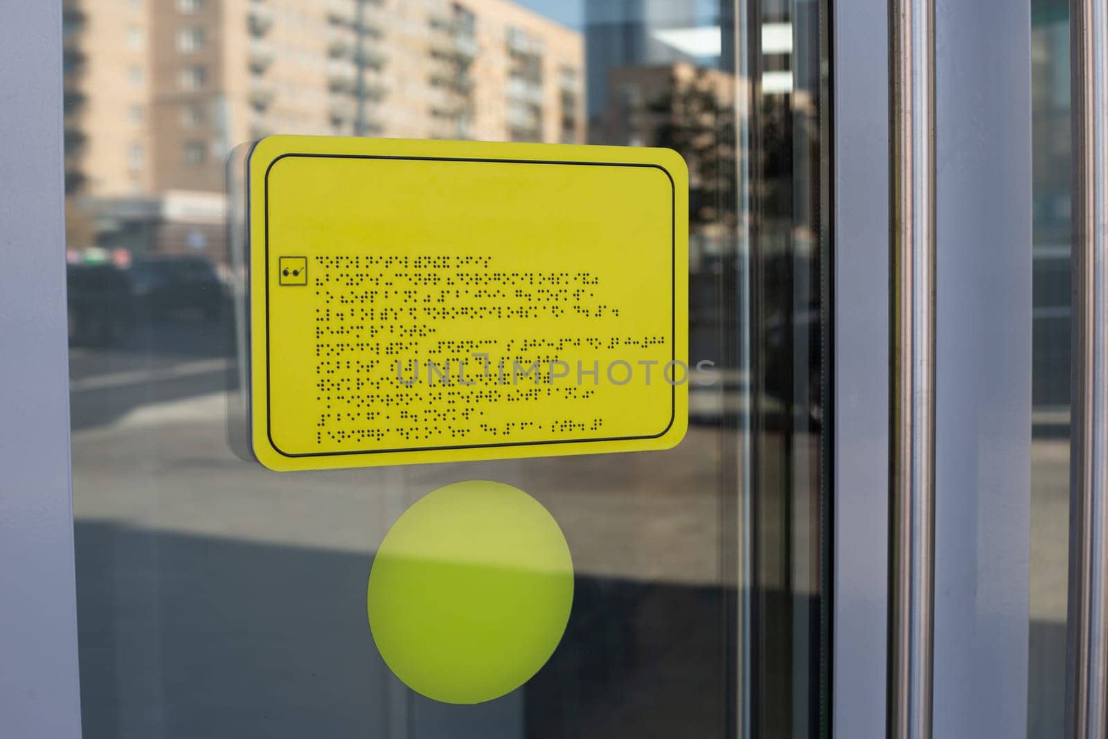 Yellow sign with black writing braille text. The sign is in language for blind people. Means of communication with people with disabilities on sign on door on entrance to the building