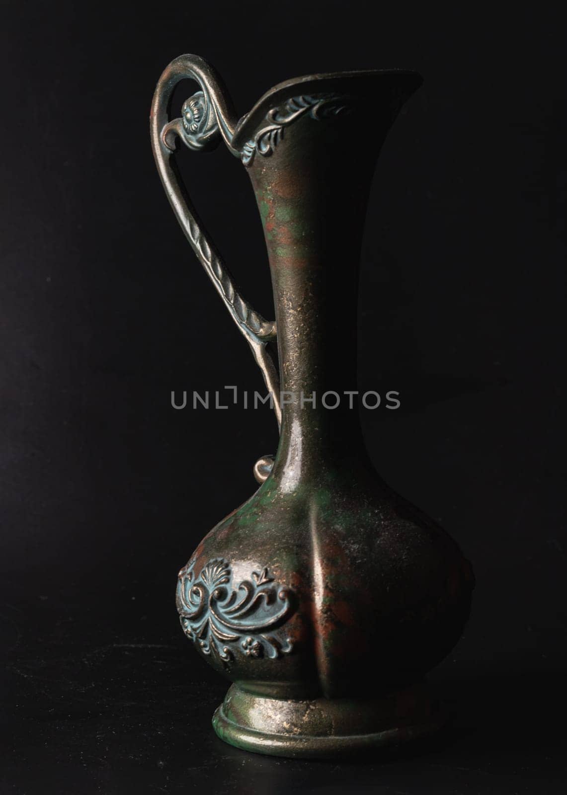 Bangkok, Thailand - 17 Sep, 2024 - Antique carved iron jug or vase on Black background.  Light and Shadow, Space for text, Selective focus.