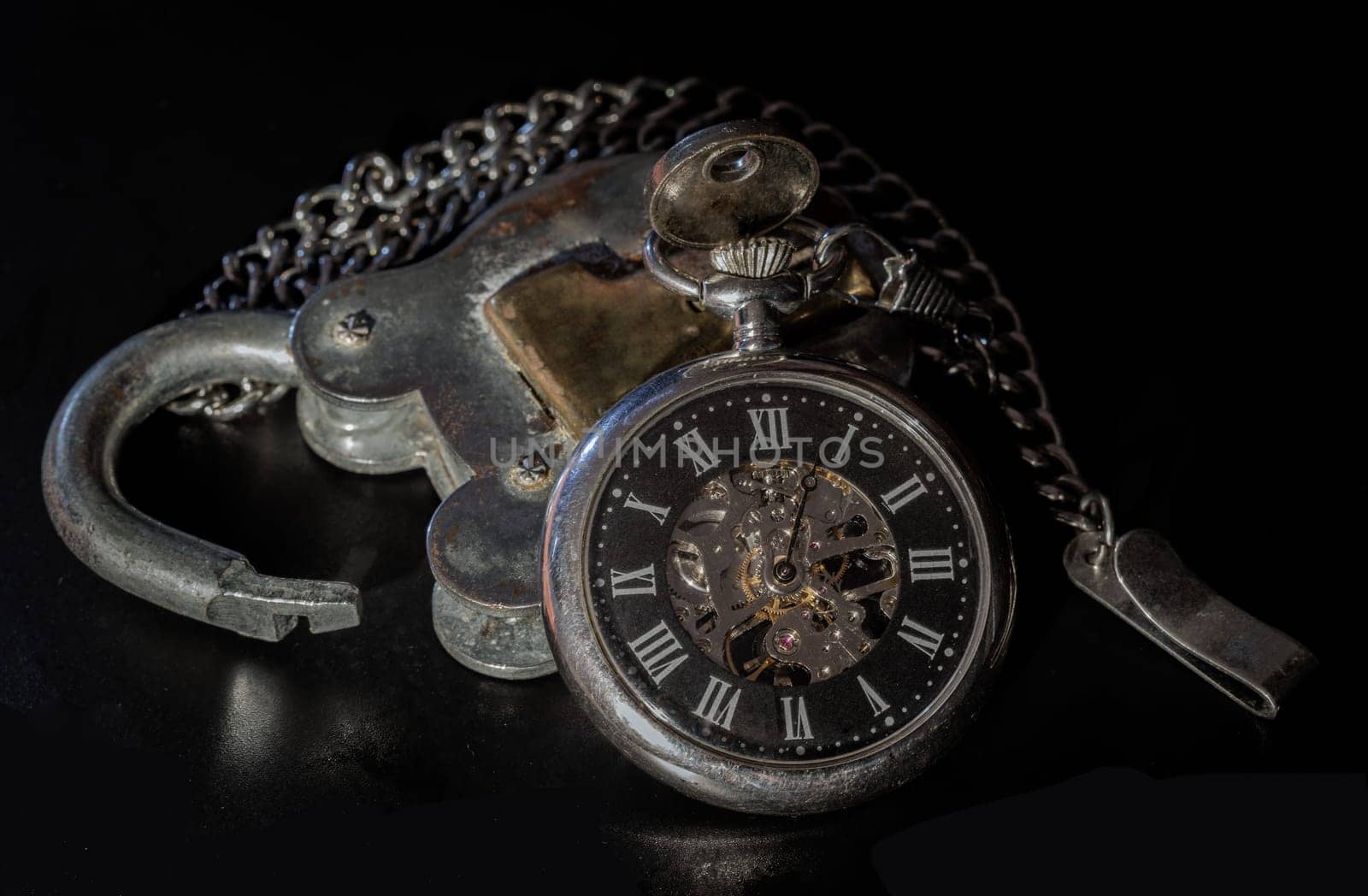 Bangkok, Thailand - 18 Sep, 2024 - A retro pocket watch on Old vintage iron padlock on dark background. Vintage style, Light and Shadow, Space for text, Selective focus.