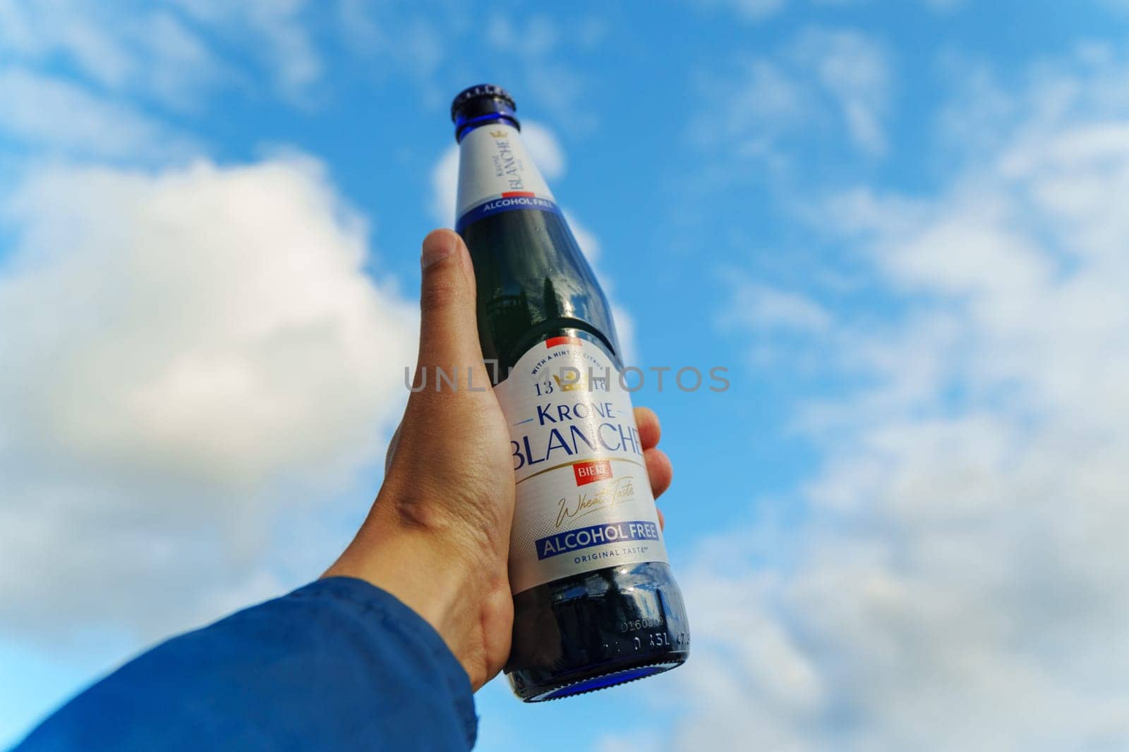 Tyumen, Russia-August 10, 2024: A person holding a bottle of alcohol-free Krone Blanche on a swing in a park during daylight