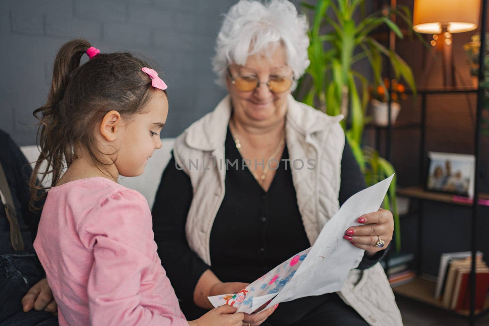 A young girl shares her colorful drawing with a smiling grandmother.