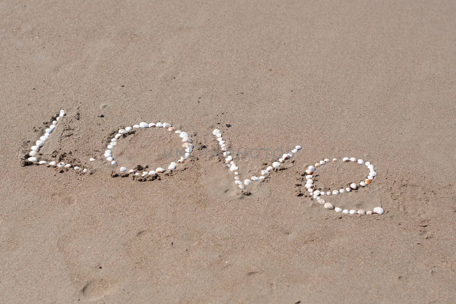 the inscription love on the wet sand of the sea beach in Turkey, lined with white shells, a love message, a declaration of love