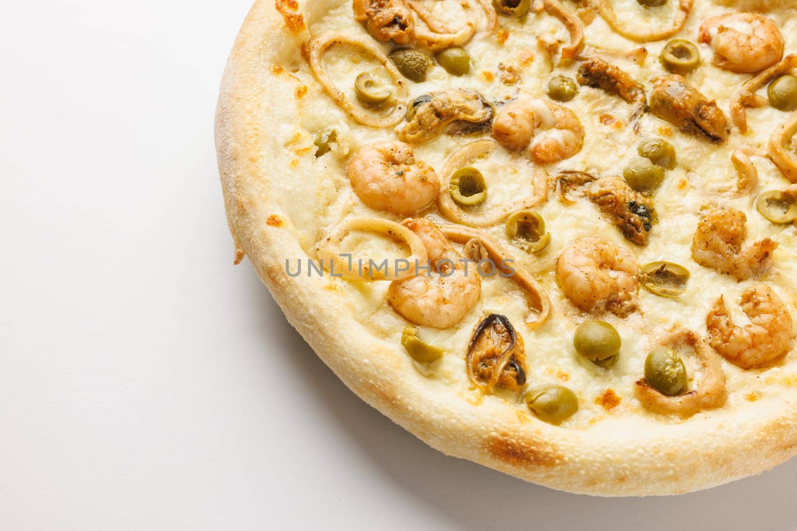 Close-up of a seafood pizza with shrimp, olives, and onions on a white background.