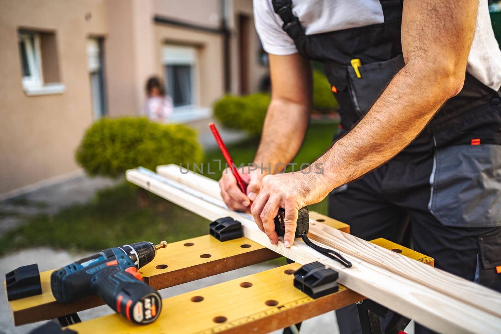 Unrecognizable men measuring wooden plank outdoors.