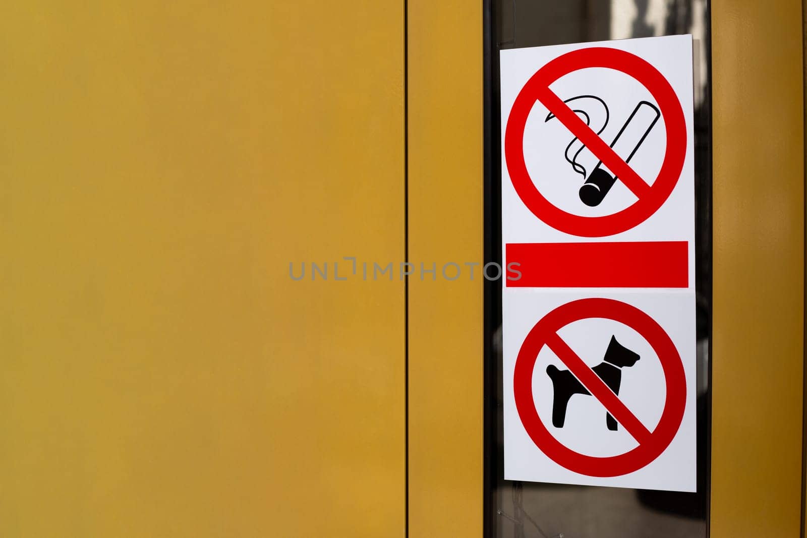 Signs prohibiting smoking and entry into building with dogs. Restricted area with no access for pets. Crossed out cigarette and dog on sticker on building door