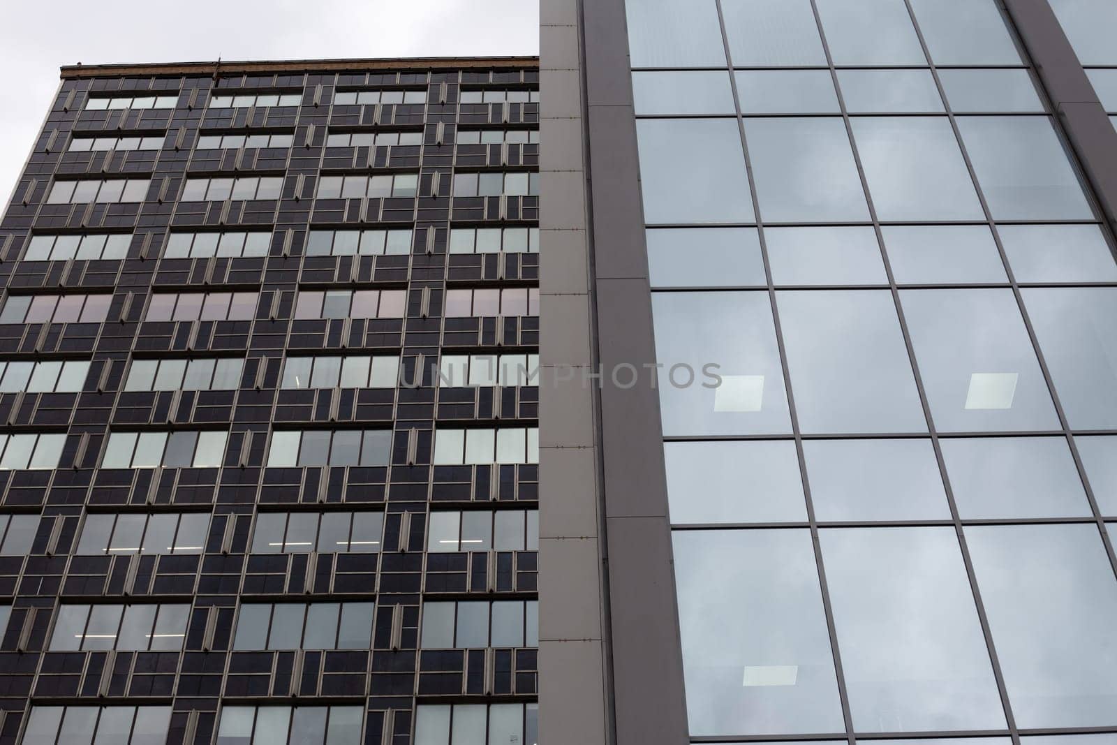 Glass facades of tall office buildings against cloudy gray sky. Office buildings for businessmen in sad atmosphere