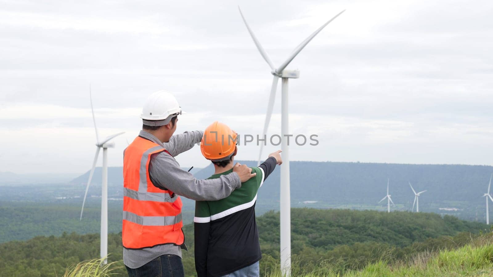 Engineer with his son on a wind farm atop a hill or mountain in the rural. Progressive ideal for the future production of renewable, sustainable energy. Energy generation from wind turbine.