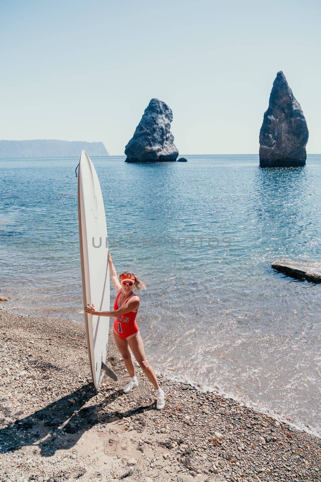 Woman sea sup. Close up portrait of happy young caucasian woman with blond hair looking at camera and smiling. Cute woman portrait in red bikini posing on sup board in the sea by panophotograph