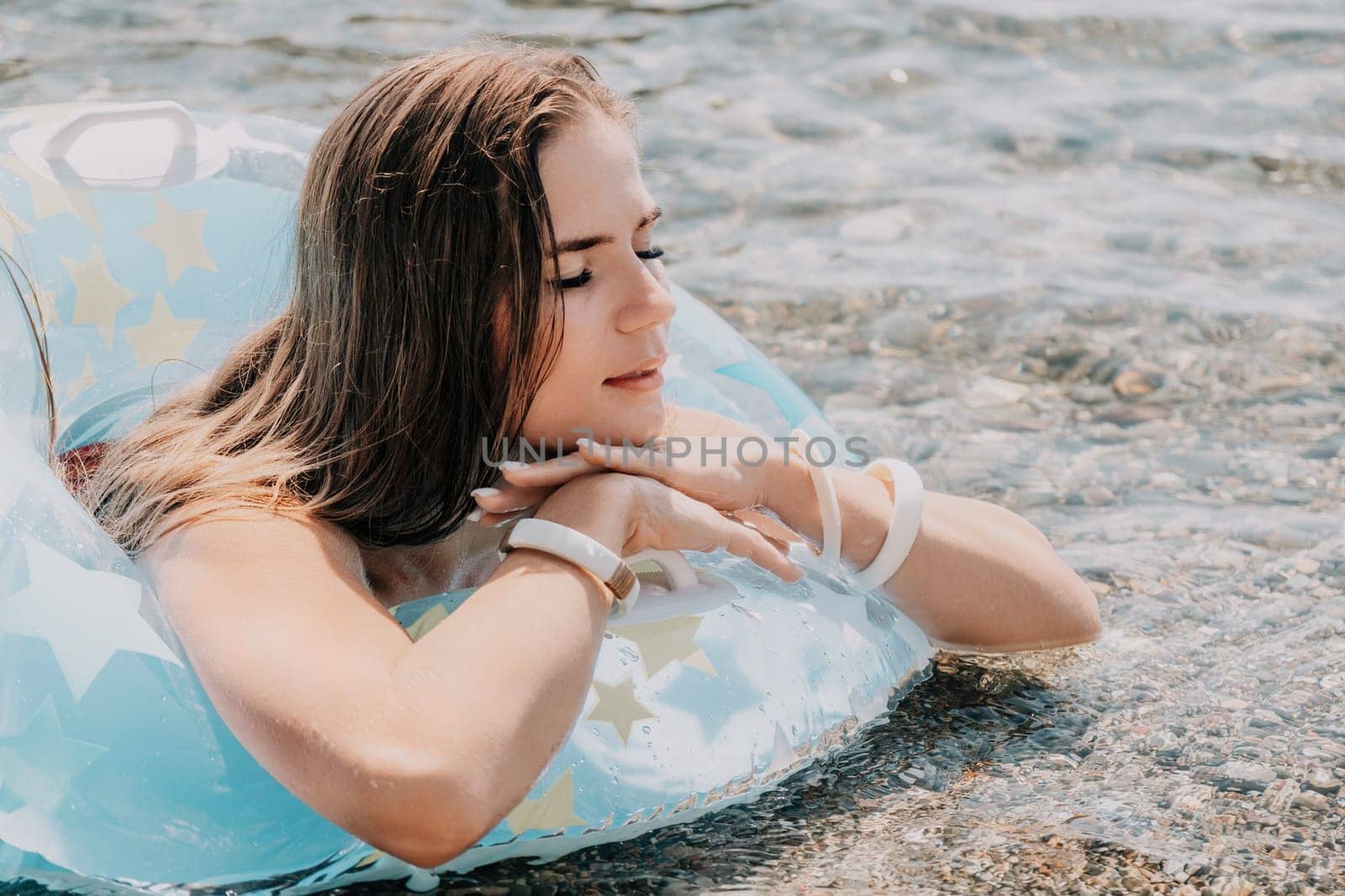 Woman summer sea. Happy woman swimming with inflatable donut on the beach in summer sunny day, surrounded by volcanic mountains. Summer vacation concept