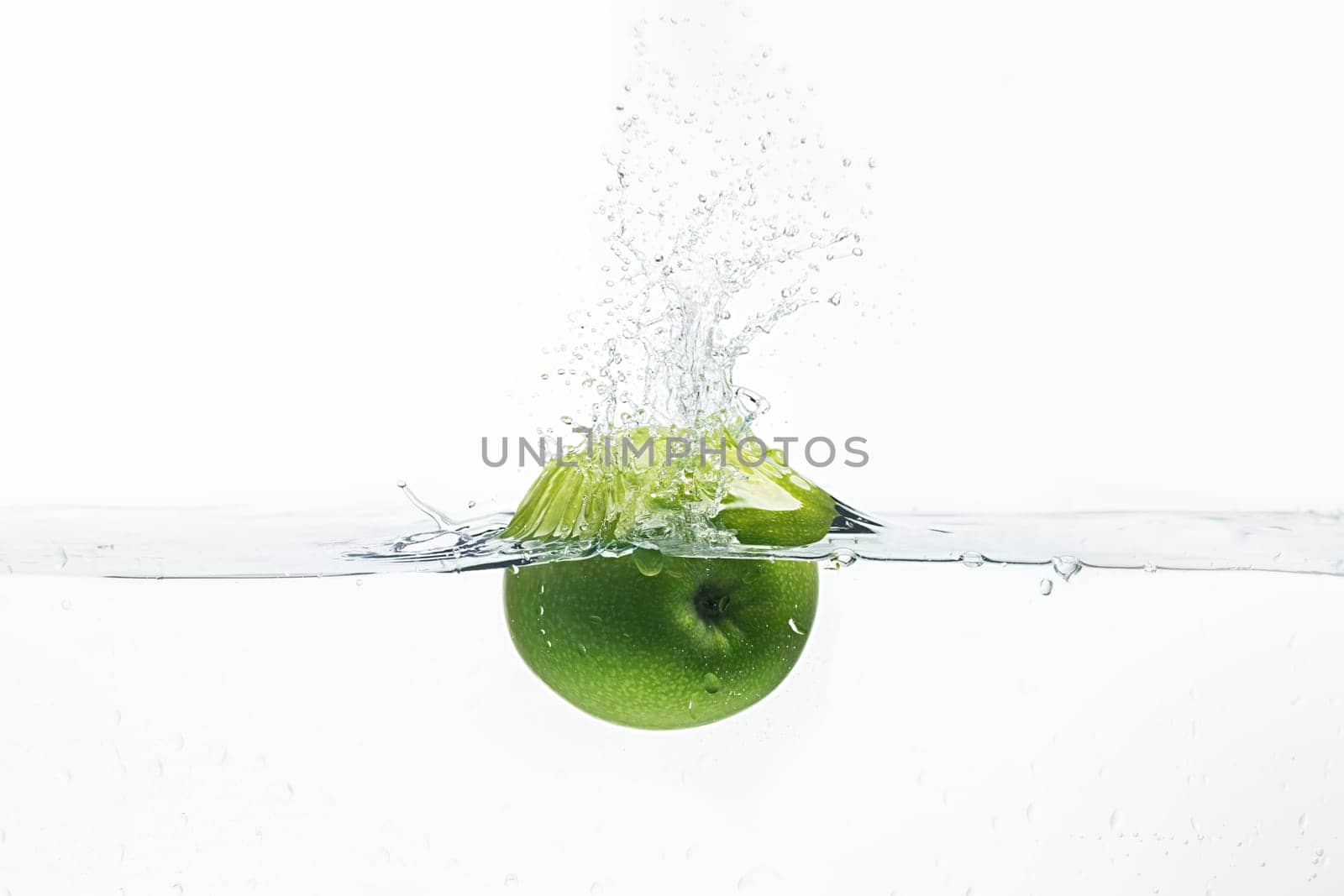 Green apple thrown in water from top with splashes above it