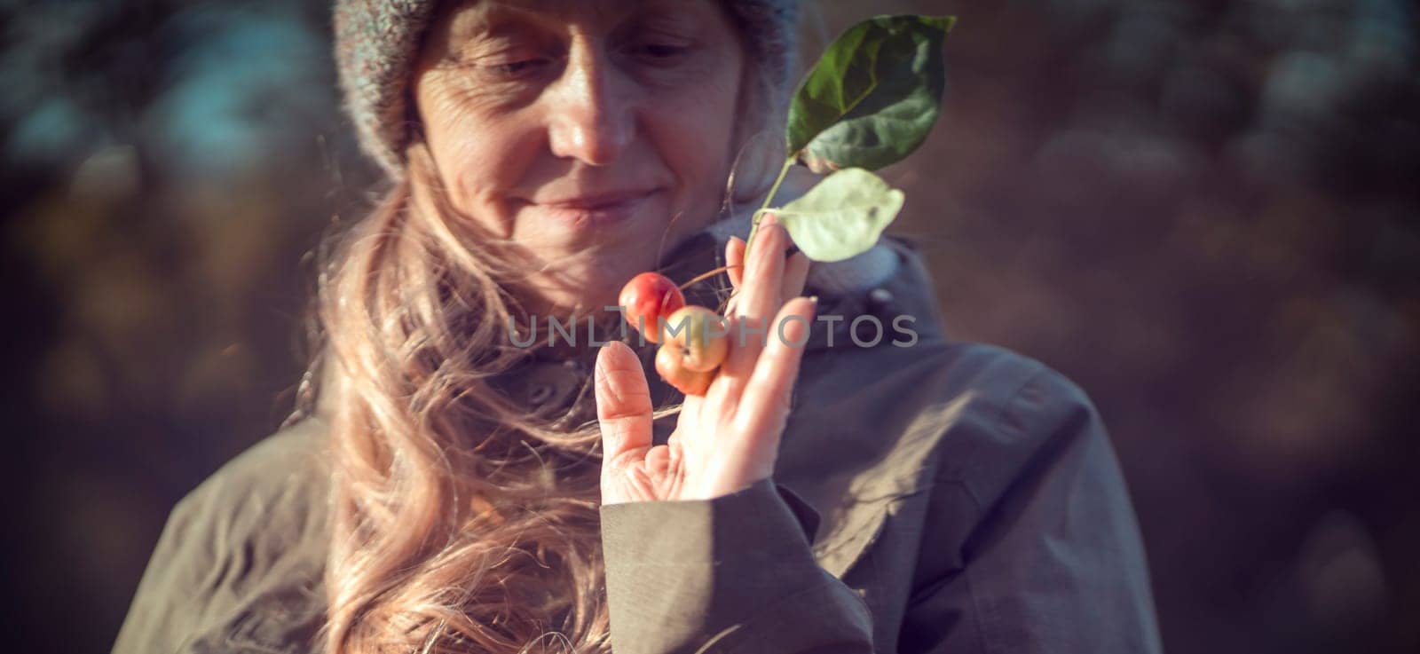 An elderly 60 beautiful woman with a kind smile is walking outdoors on a sunny autumn day, a happy old lady, a grandmother takes care of her appearance, natural beauty with wrinkles portrait closeup.