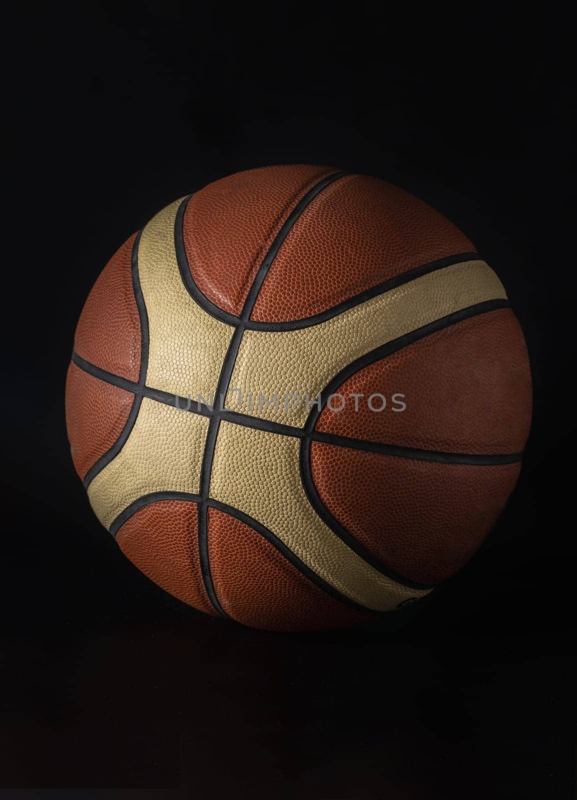 Basketball ball in minimalist style isolated on dark background. Basketball ball leather texture with bumps pattern background, Light and Shadow, Space for text, Selective focus.