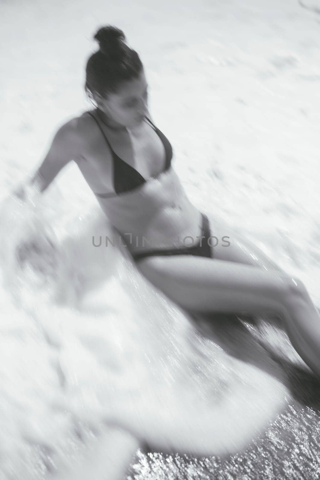 A peaceful moment is captured of a woman sitting quietly by the water, enjoying the calm beach atmosphere