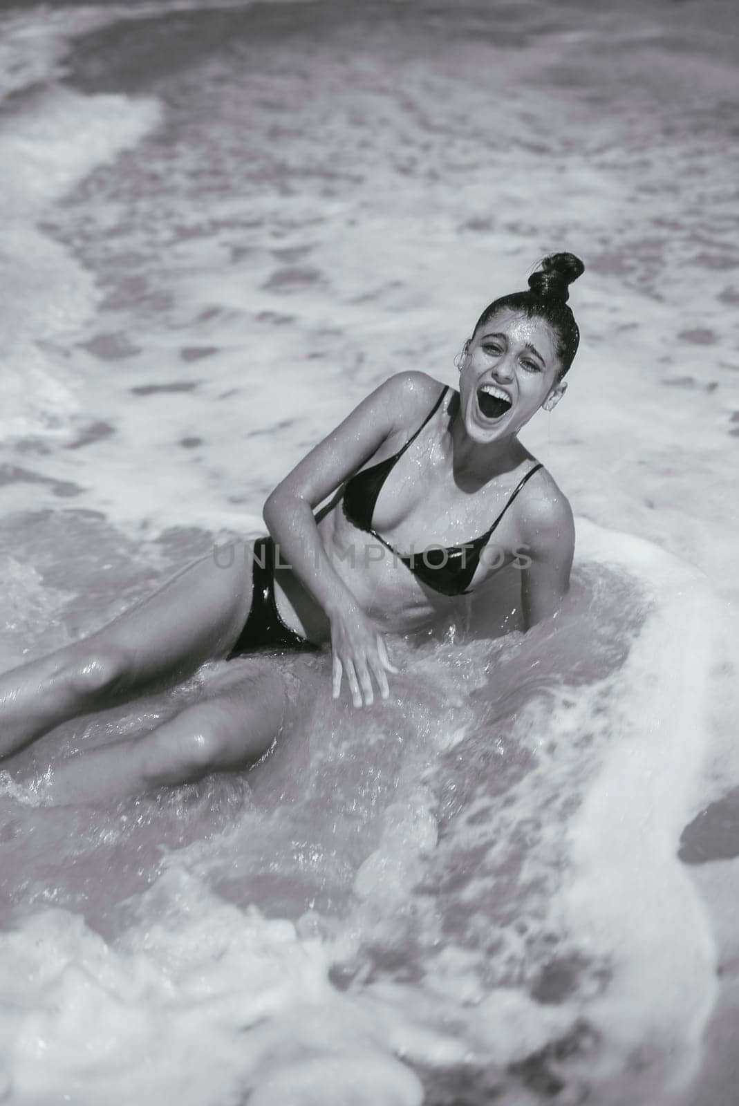 A truly joyful and unforgettable moment on the sandy beach, where laughter seamlessly meets the refreshing ocean waves