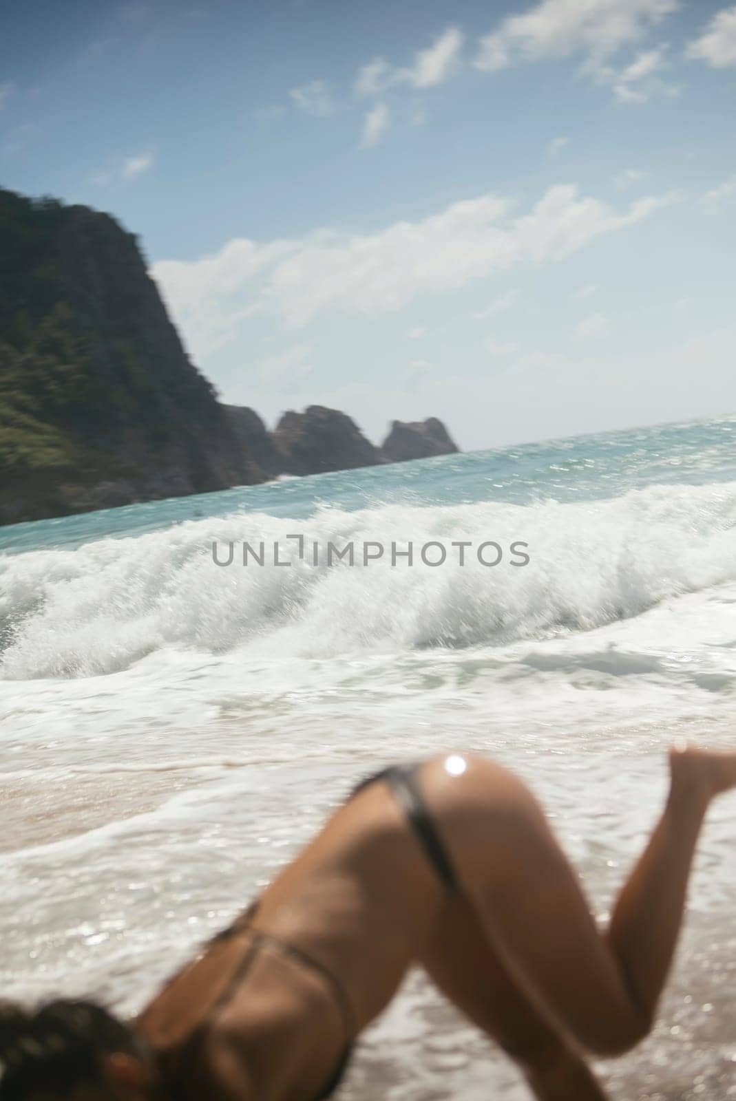 A joyful scene unfolds at the beach with waves crashing as a woman plays exuberantly in the refreshing water