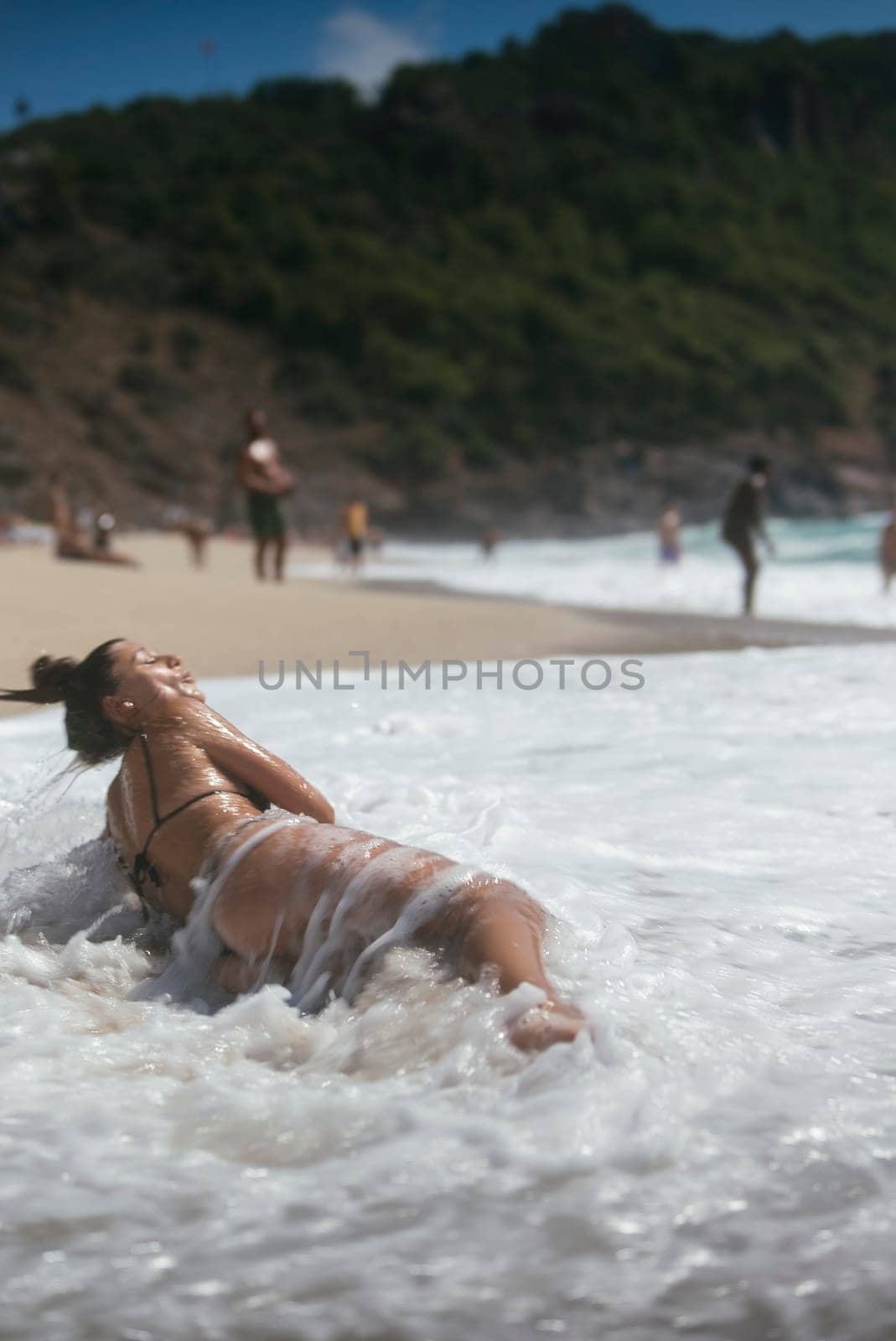 A tranquil and serene beach scene showcases gentle waves while a woman enjoys the warm sun and surf activities