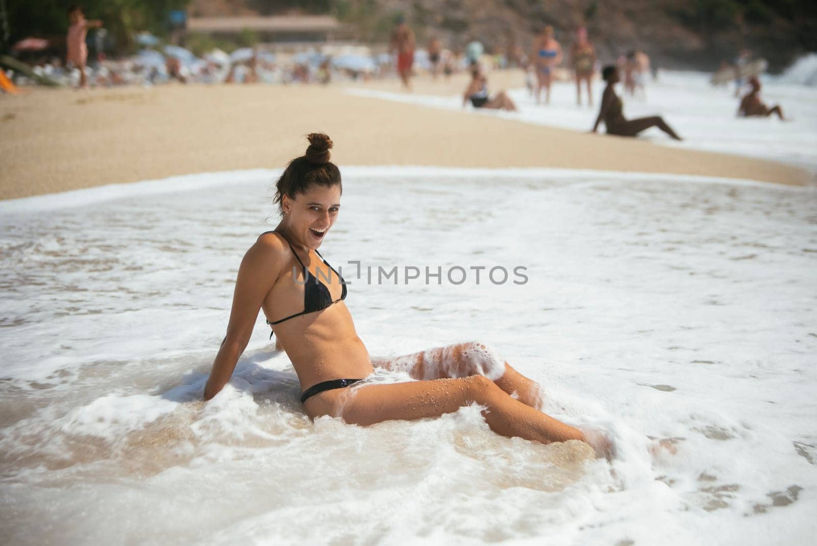 A serene beach scene of a woman relaxing in gentle waves, evoking strong summer vibes and tranquility