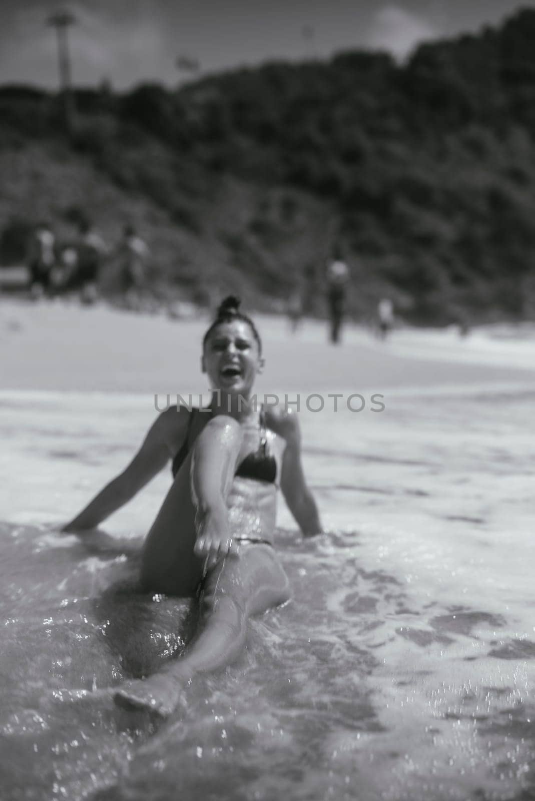 A woman is relaxing in the gentle ocean waves, thoroughly enjoying a serene beach day under the warm sun