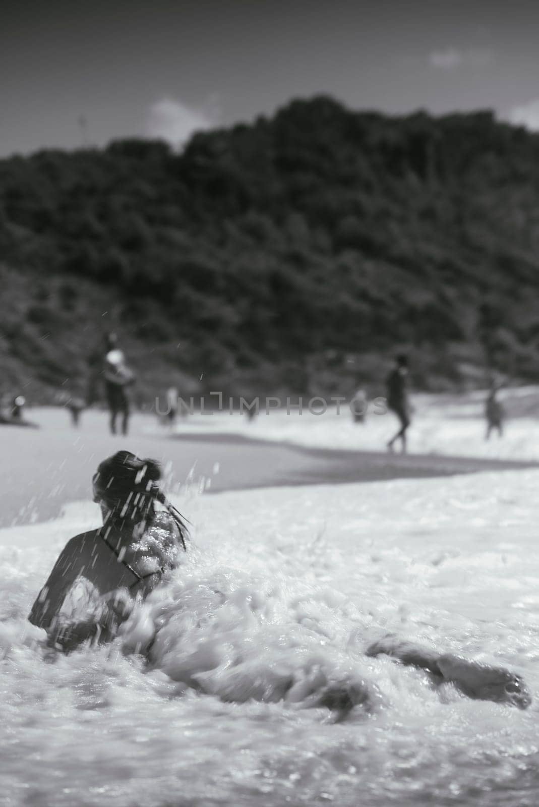 A serene moment of a woman playfully interacting with the waves at the beach, evoking tranquility and joy