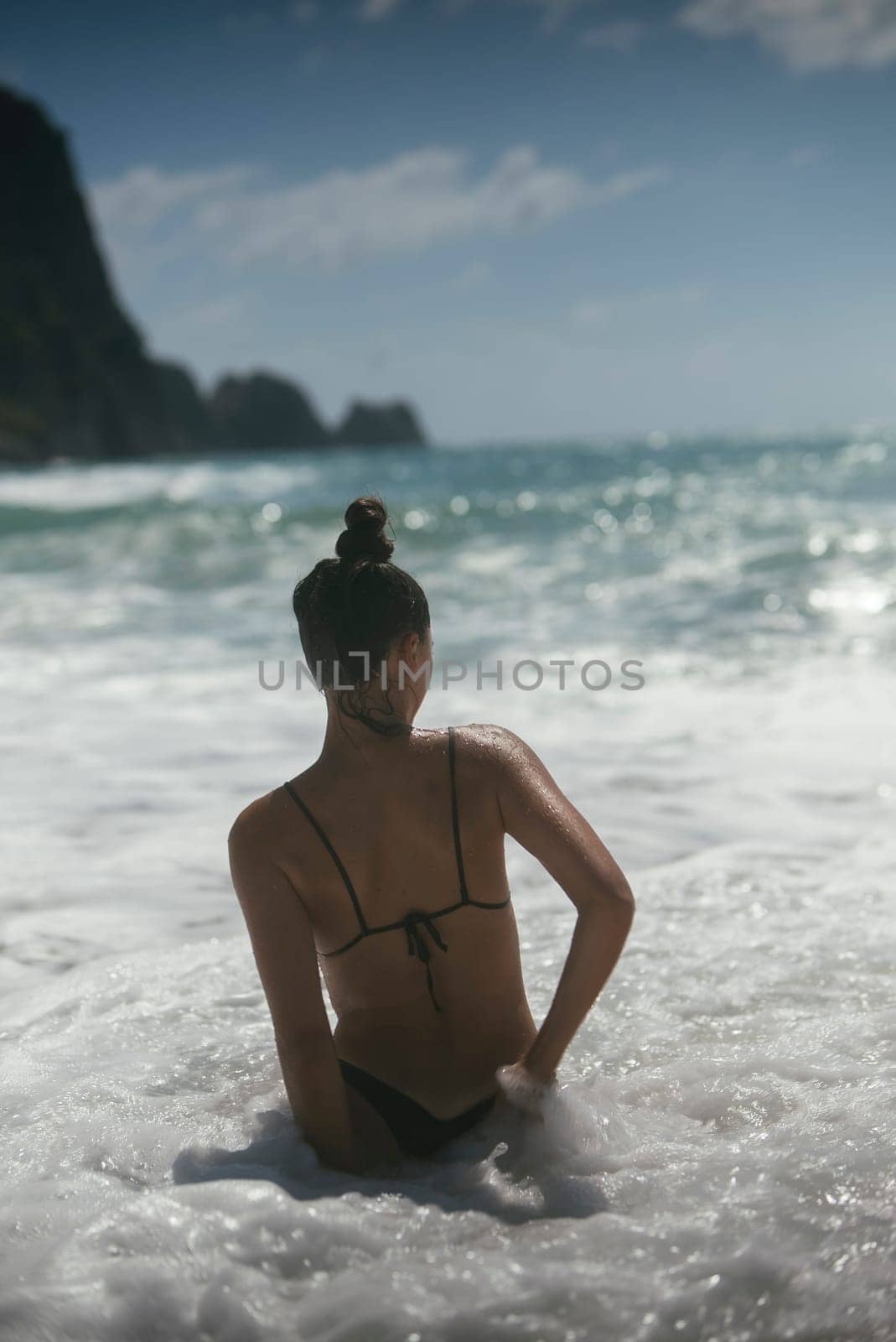 A woman enjoys soothing ocean waves, embodying tranquility and beauty in a picturesque coastal setting