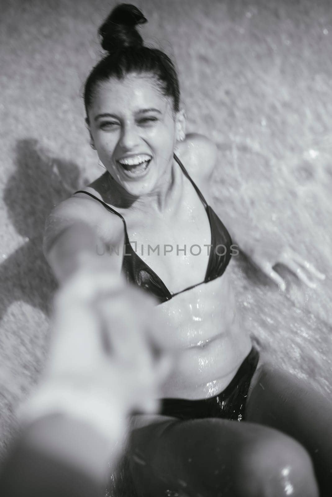 A young woman, full of joy and laughter, is playfully enjoying herself in the refreshing water, embodying vitality
