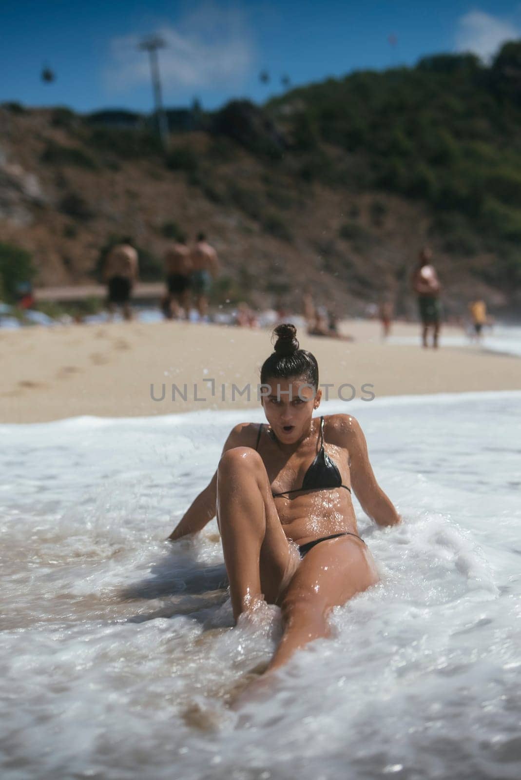 A beautiful and serene beach scene showcasing a woman who is enjoying the waves, sunshine and the warmth of the sun