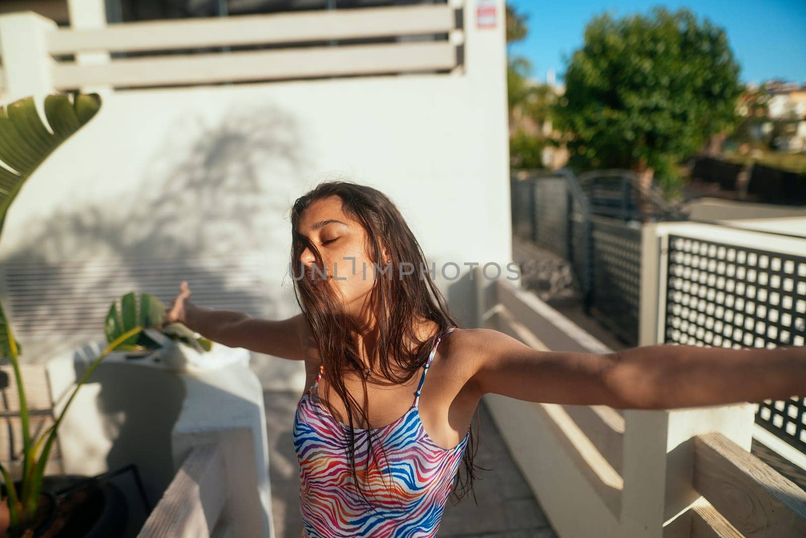 A carefree woman fully enjoys the sunny day while wearing colorful swimwear, exuding pure happiness and freedom